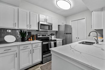 a white kitchen with stainless steel appliances and marble counter tops
